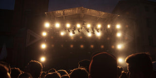 Lit festival stage and crowd at a concert at dusk