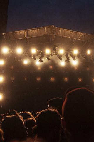 Lit festival stage and crowd at a concert at dusk