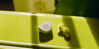 Happy Ears reusable earplugs and case on a lime-green travel suitcase