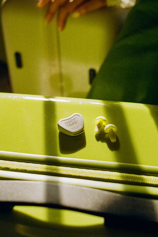 Happy Ears reusable earplugs and case on a lime-green travel suitcase